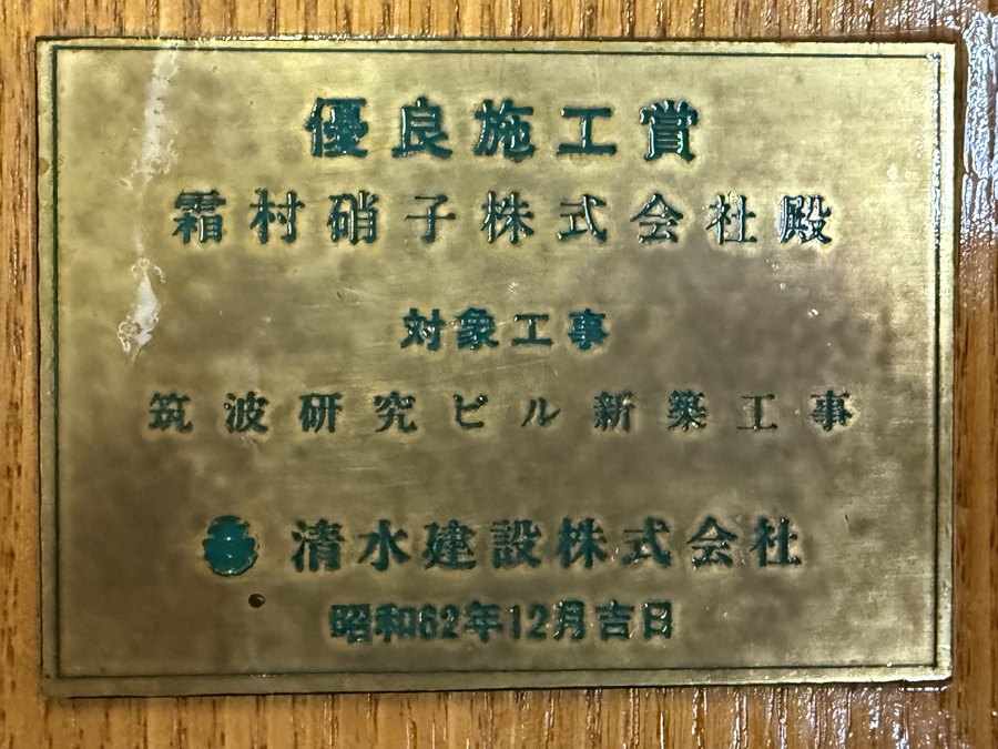 盾の銘板。優良施工賞 霜村硝子株式会社殿 対象工事 筑波研究ビル新築工事 清水建設株式会社 昭和62年12月吉日
